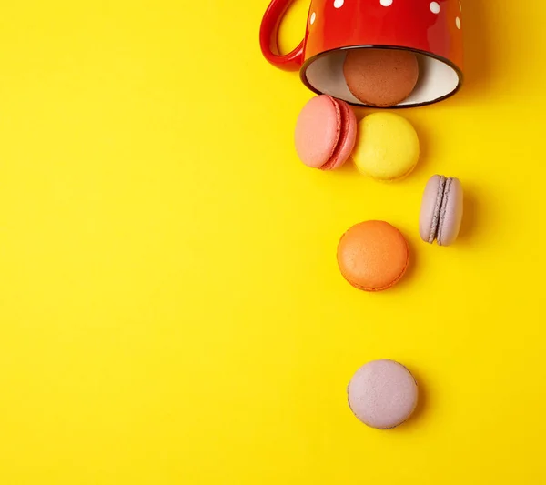 Macarons ronds multicolores tombant d'une tasse en céramique rouge — Photo