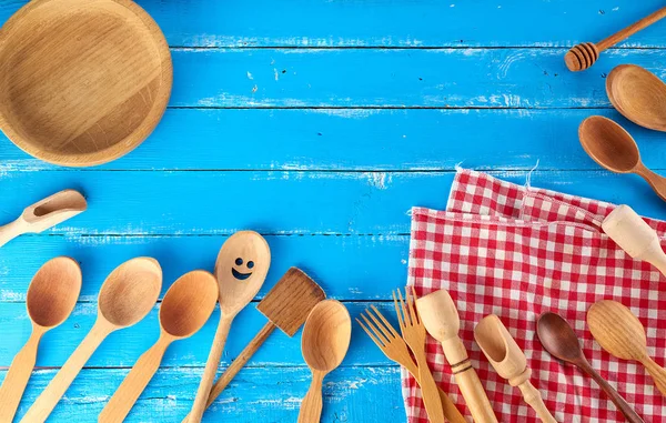 Muchas cucharas de madera diferentes, tenedores y plato vacío en una ba azul — Foto de Stock