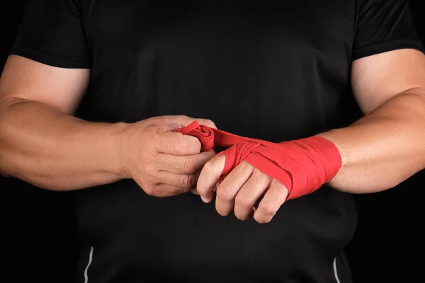 Athlete stand in black clothes and wrap his hands in red textile — Stock Photo, Image