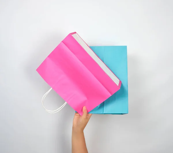 Mão feminina segurando quatro sacos de embalagem de compras de papel colorido — Fotografia de Stock