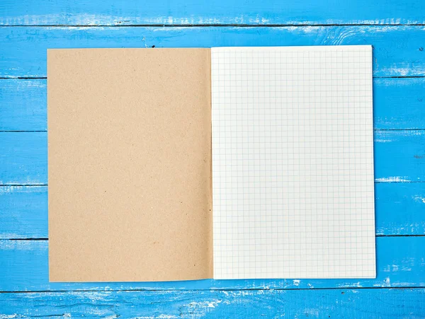Open gecontroleerde school notitieboekje op blauwe houten achtergrond — Stockfoto