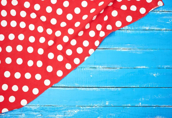 Asciugamano tessile rosso con cerchi bianchi su uno sfondo di legno blu — Foto Stock