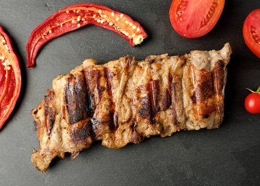 siyah bir tahta üzerinde ızgara domuz kaburga, taze kırmızı domates