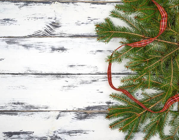 Ramas verdes de un árbol de Navidad y una cinta roja — Foto de Stock