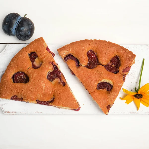 Tranches de biscuit gâteau aux prunes sur une planche de bois blanc — Photo