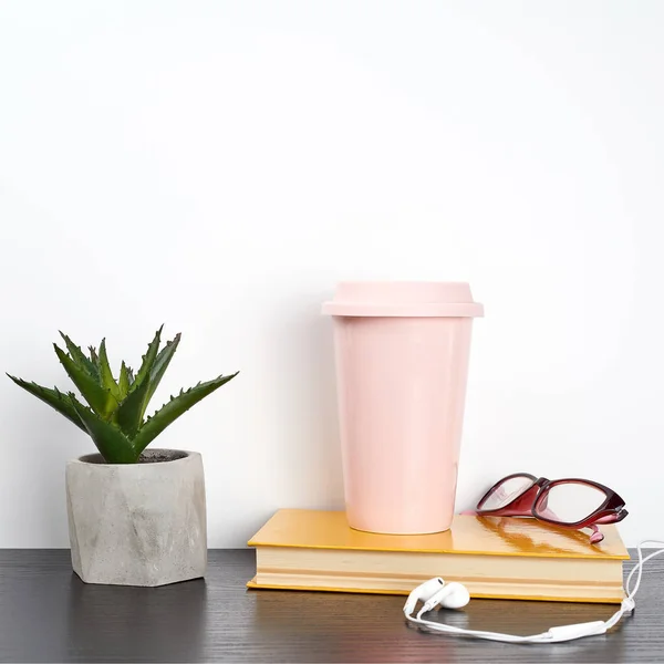 closed book and pink ceramic glass with coffee on a black table