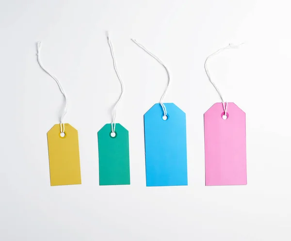 Étiquettes en papier coloré sur une corde blanche, fond blanc — Photo