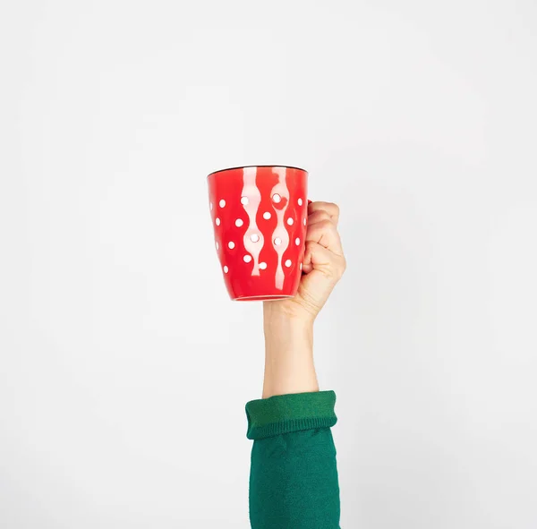 Taza de cerámica roja en una mano femenina sobre un fondo blanco — Foto de Stock