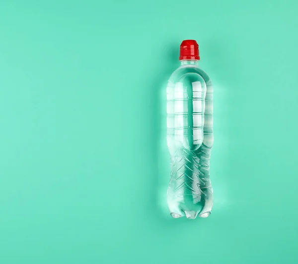 Botella de plástico transparente con agua dulce en un fondo verde — Foto de Stock