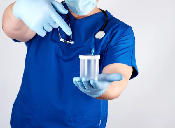 Doctor en uniforme azul y guantes de látex está sosteniendo un plas vacío —  Fotos de Stock