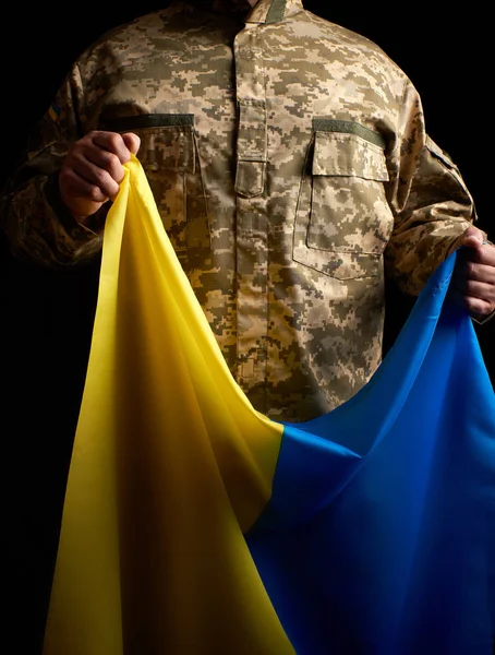 Soldado ucraniano segura em sua mão a bandeira amarelo-azul do — Fotografia de Stock