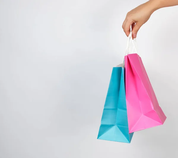 Mano femenina sosteniendo bolsas de embalaje de papel de colores — Foto de Stock