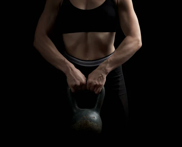 Girl of athletic appearance holds an iron kettlebell in front of — Stock Photo, Image