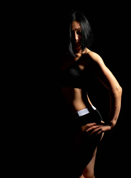 Menina adulta com uma figura esportiva em sutiã preto e shorts pretos st — Fotografia de Stock