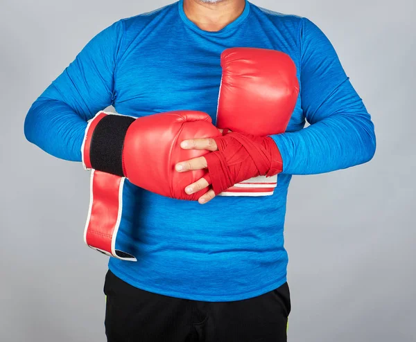 Atleta en ropa azul, las manos se rebobinan con banda textil roja — Foto de Stock