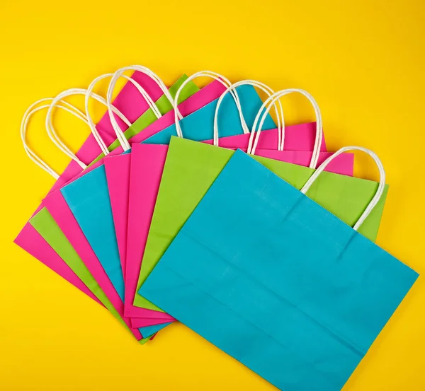Sacos de compras de papel multicoloridos com alças brancas — Fotografia de Stock