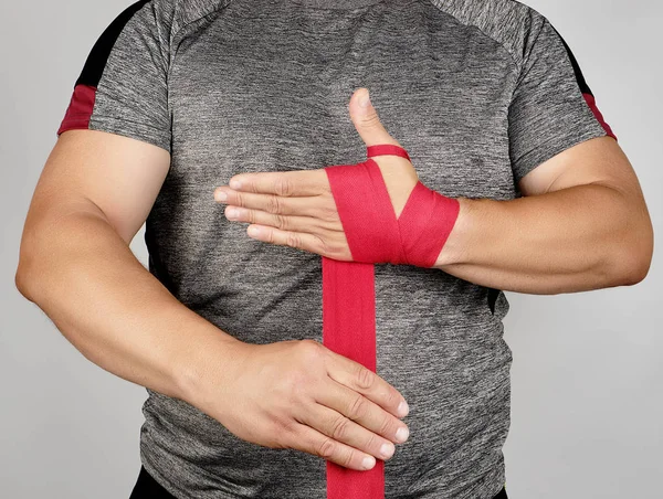 Atlet berdiri dalam pakaian abu-abu dan membungkus tangannya dalam tekstil merah — Stok Foto