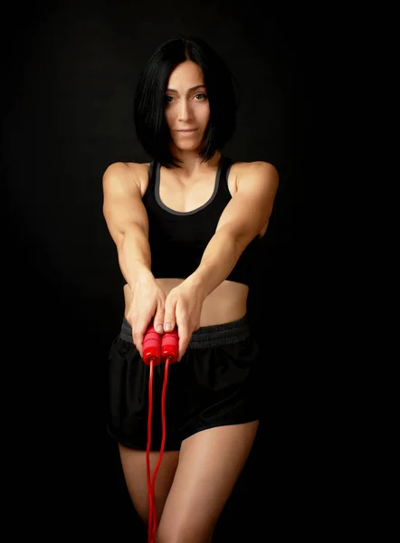 Young woman with a sports figure in black uniform holds a red ro — Stock Photo, Image