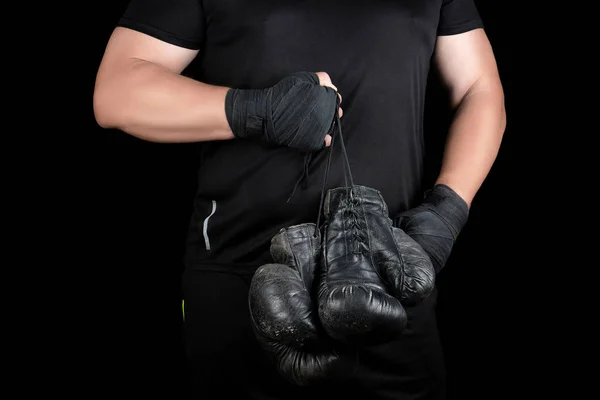 Спортсмен в чорному одязі тримає дуже старий старовинний шкіряний чорний бо — стокове фото