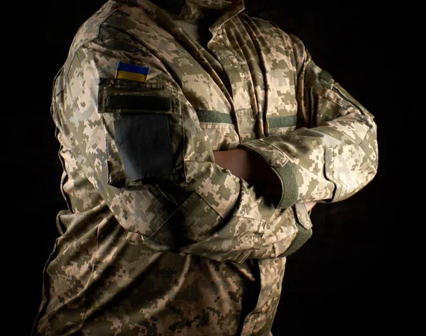 Ukrainian soldier in camouflage uniform stands with arms crossed — Stock Photo, Image