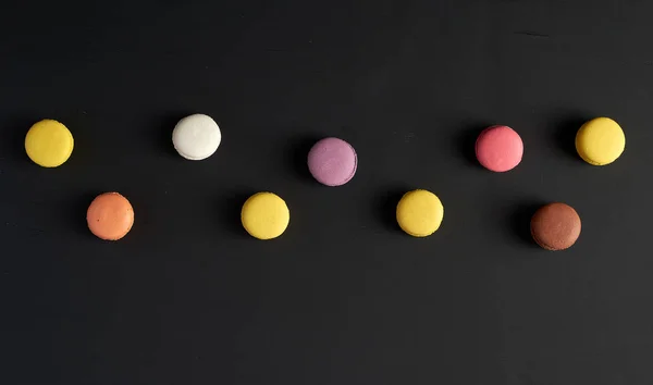 क्रीम के साथ गोल बहु रंगीन बेक्ड मैकरॉन एक पंक्ति में स्थित हैं — स्टॉक फ़ोटो, इमेज