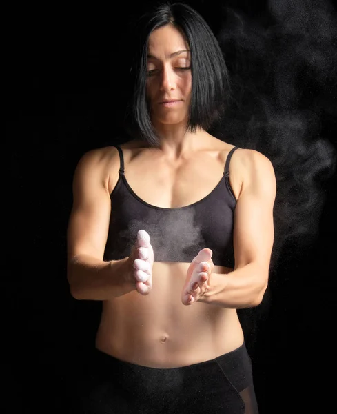 Girl with a sports figure dressed in a black top claps in her ha — Stock Photo, Image