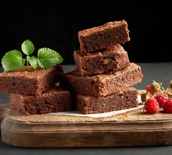 Стопка обжаренных квадратных кусочков шоколадного пирожного на коричневом — стоковое фото