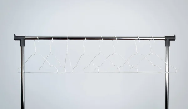 Perchas de metal blanco vacío cuelgan en una barra de cromo, fondo blanco —  Fotos de Stock