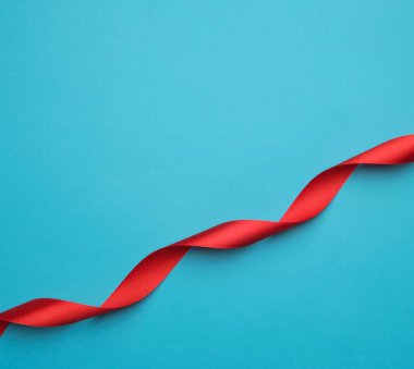 Mavi arkaplanda kıvrımlı kırmızı saten kurdele