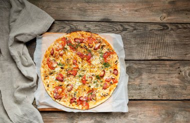 Kızarmış sosisli, mantarlı, domatesli fırında pizza.