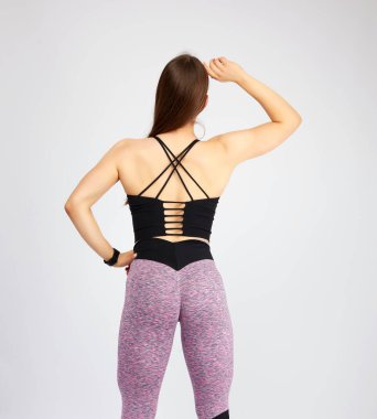 Spor figürlü bir kız kollarını kaldırmış, arkasında duruyor.