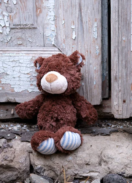 Kleine teddybeer zit op de stoep bij een oude deur met cra — Stockfoto