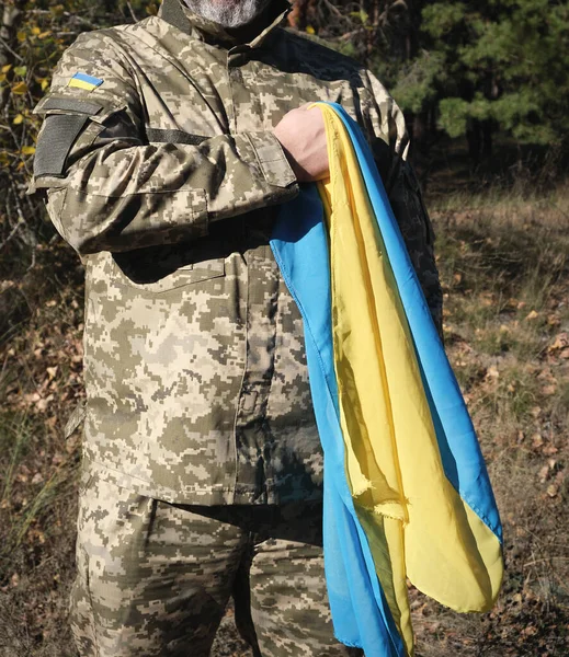 Soldado ucraniano segura em sua mão a bandeira amarelo-azul do — Fotografia de Stock