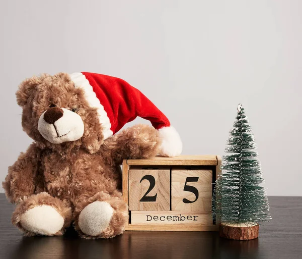 Ursinho de pelúcia marrom em chapéu vermelho, mesa calendário de madeira com a data — Fotografia de Stock