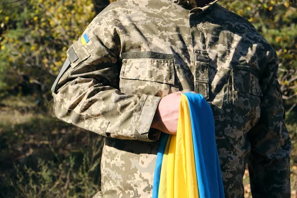 Soldado ucraniano sostiene en su mano la bandera amarillo-azul de la — Foto de Stock