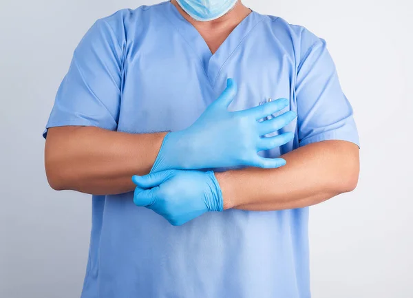 Doctor masculino en uniforme azul se pone en las manos blanco estéril tarde — Foto de Stock