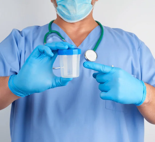 Doctor en uniforme azul y guantes de látex está sosteniendo un plas vacío —  Fotos de Stock