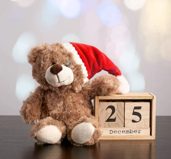 Ursinho de pelúcia marrom em chapéu vermelho, mesa calendário de madeira com a data — Fotografia de Stock