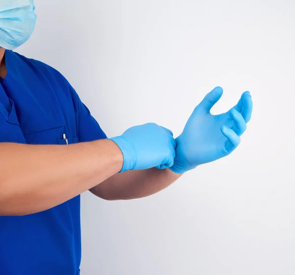 Doctor masculino en uniforme azul se pone en las manos blanco estéril tarde — Foto de Stock