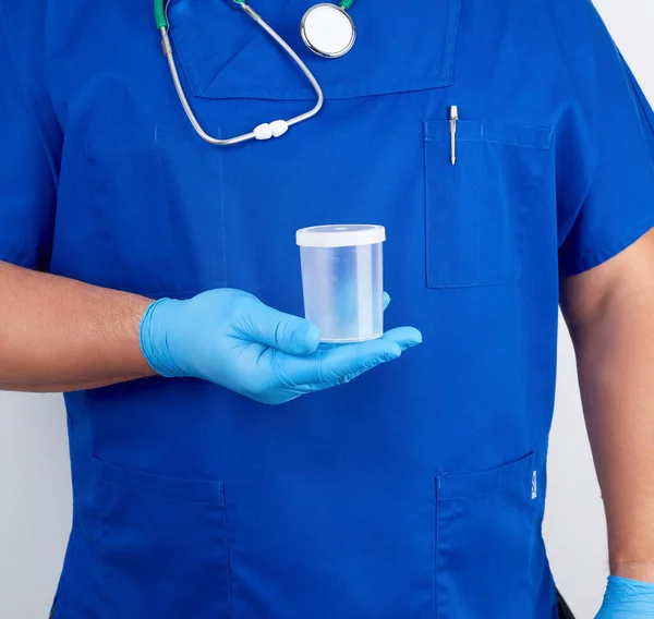 Lékař v modré jednotné a latexové rukavice drží prázdné plas — Stock fotografie