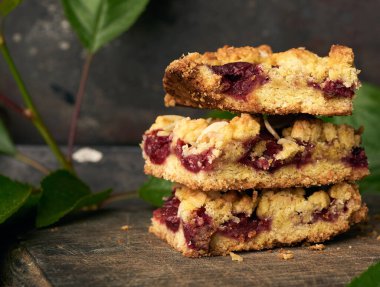 Tahtada kiraz olan kare şeklinde turta yığını, lezzetli bir tatlı.