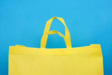 Mavi zemin üzerinde yeniden kullanılabilir sarı viskoz torbası, plastik atık azaltma kavramı
