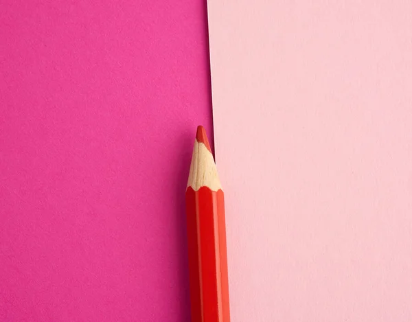 red wooden pencil on a colored background, top view, object for drawing