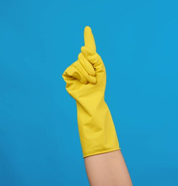 Sarı kauçuk eldiven, kadın eli giyinmek için, mavi arka plan, vücudun bir kısmı kaldırılmış.