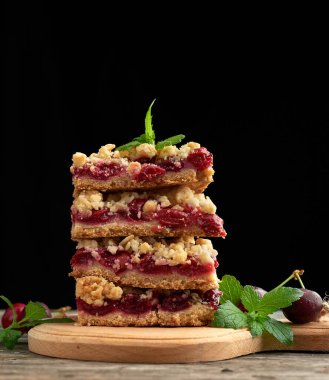 Kırmızı kirazlı, siyah arkaplanlı, lezzetli parçalanmış bir turta yığını.