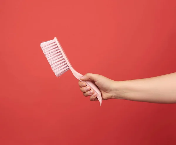 Female Hand Holds Pink Plastic Cleaning Brush Red Background — Stock Photo, Image