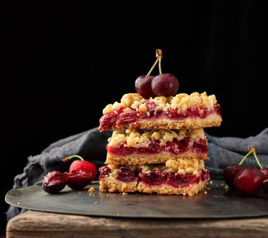 Kırmızı kirazlı, siyah arkaplanlı, lezzetli parçalanmış bir turta yığını.