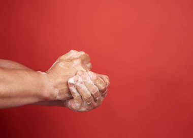 Beyaz köpüklü iki erkek eli, vücut hijyeni, kırmızı arka plan. 