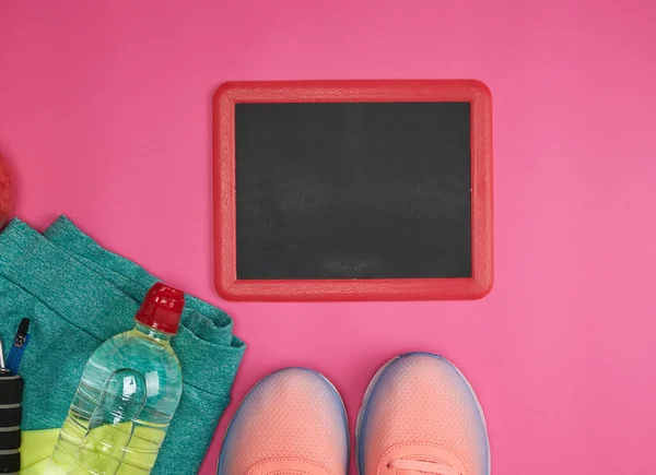 empty frame and objects and clothes for sports and fitness on a pink background, copy space