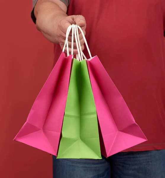 赤い服の男は白い紙袋と赤い背景と買い物と注文の配達という概念を持っています — ストック写真